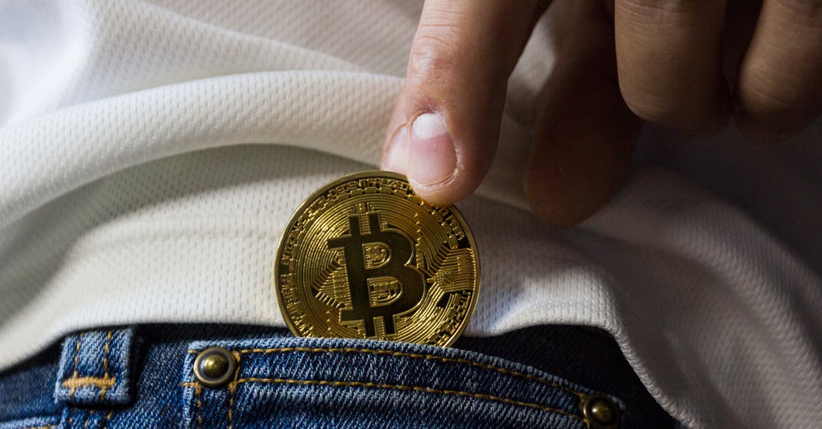 Close-up of hand putting Bitcoin in jeans pocket symbolizing cryptocurrency savings.